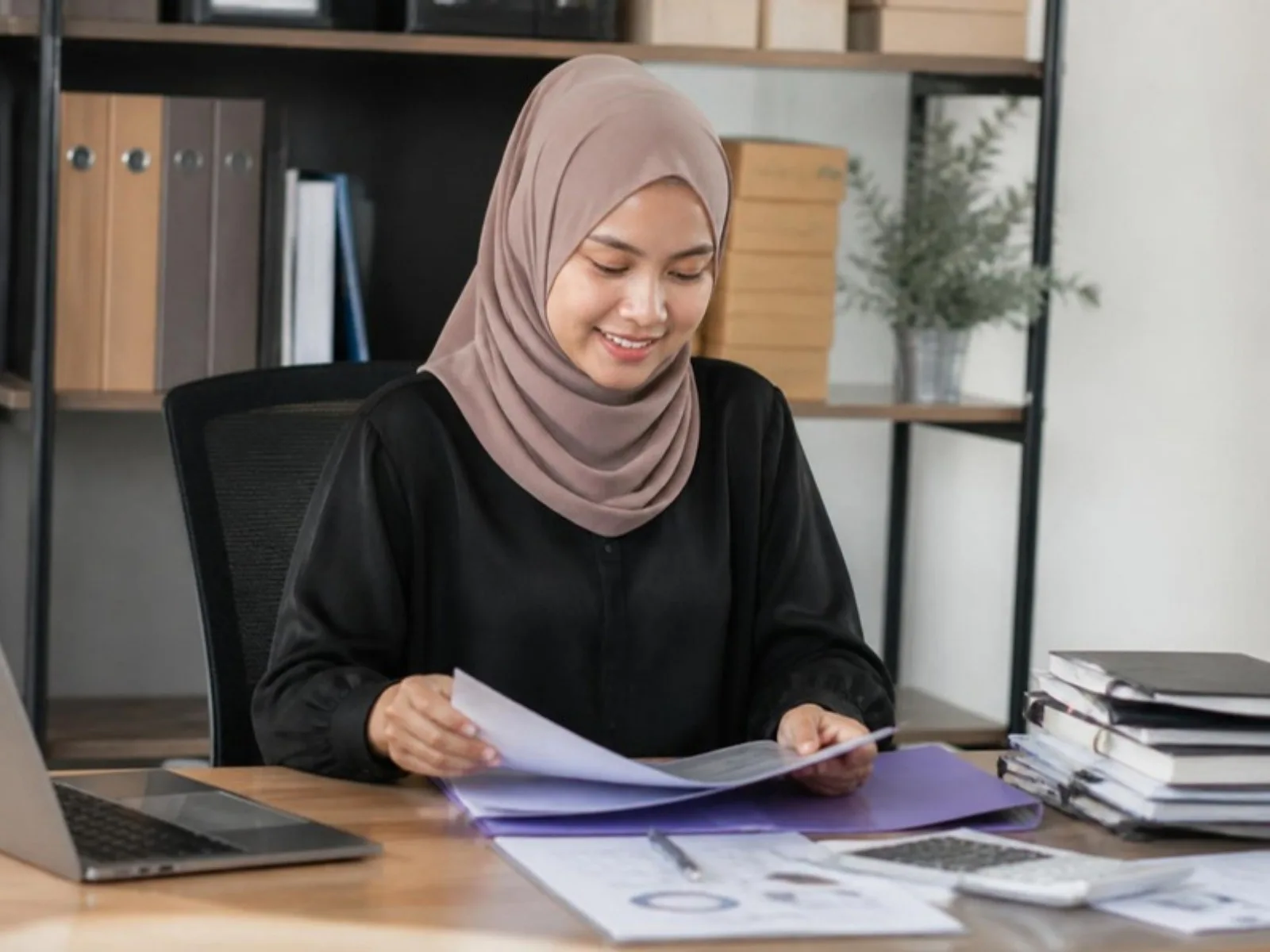 Seorang pemilik perniagaan menyusun fail dokumen perniagaan di sebuah meja